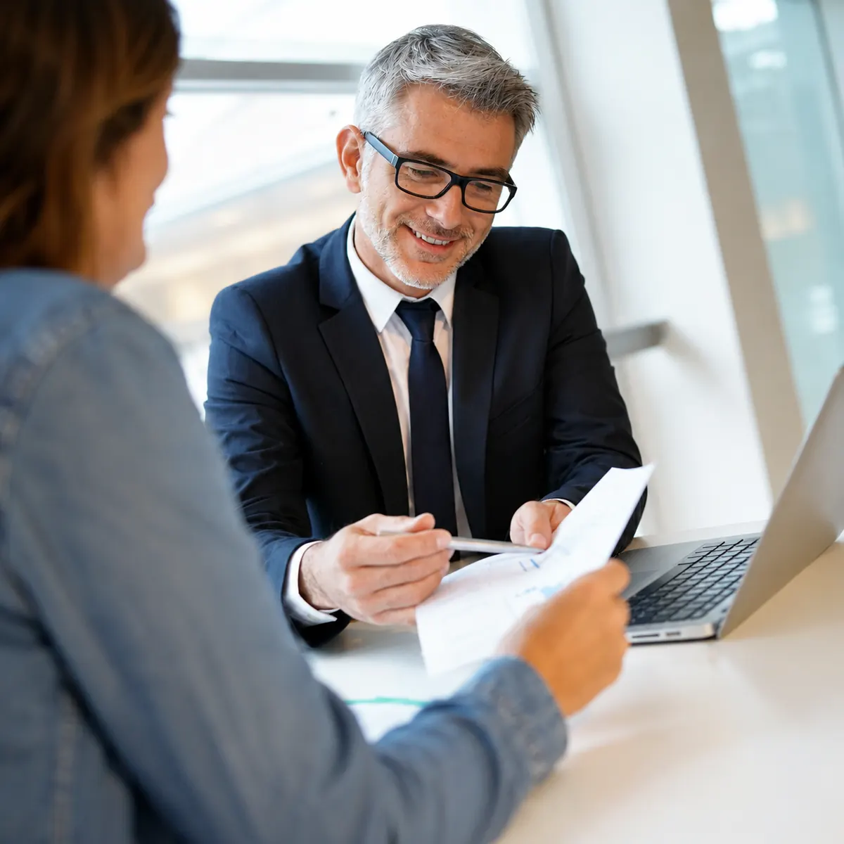 Conseiller remplissant un dossier de assistance immobilier avec maquettes de maisons